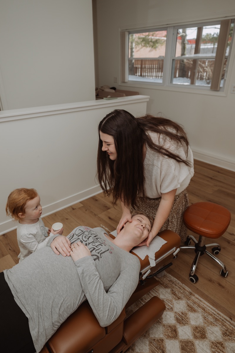 Dr. Molly Mehlman adjusting a patient with their child alongside at Grove Chiropractic Co.